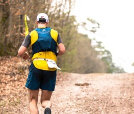 a man running down a dirt road in the woods