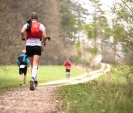 a group of people running on a trail in the woods